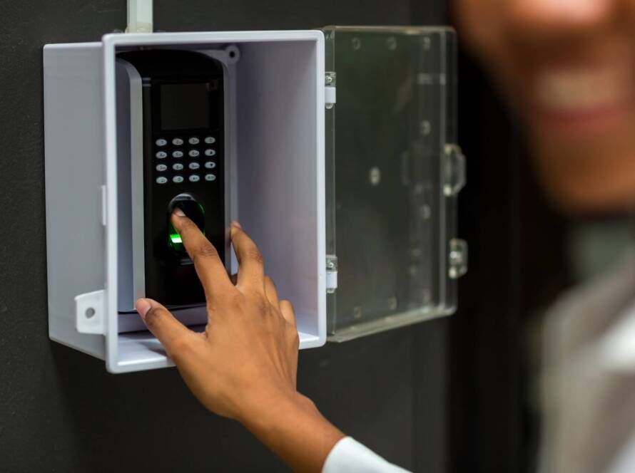 Person using biometric entry system with fingerprint scanner for secure residential or commercial gate access.