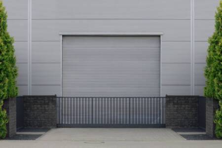 Roller door or roller shutter with application to factory, warehouse or hangar. Outside, trees on the sides